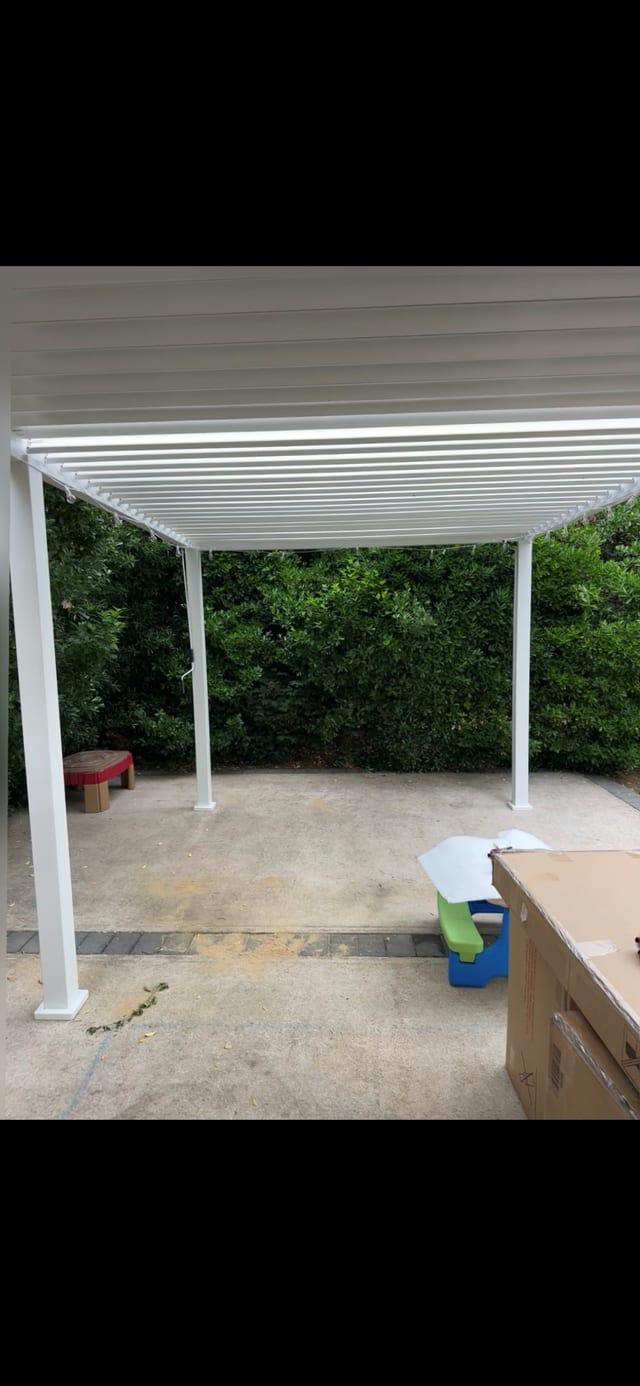 White pergola installed over a poolside patio